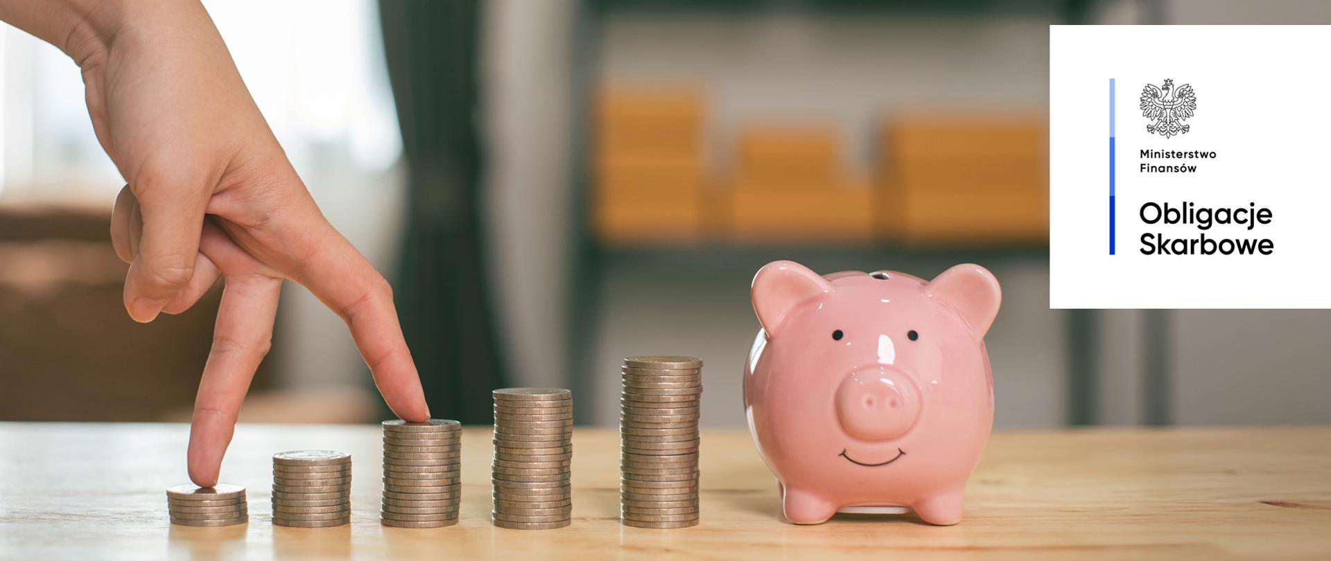 Dłoń, monety, świnka skarbonka. Ministerstwo Finansów, Obligacje Skarbowe.
