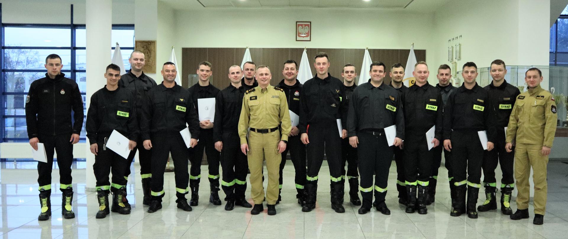 Grupowe zdjęcie uczestników szkolenia (16 strażaków) w towarzystwie Zastępcy Komendanta Centralnej Szkoły PSP oraz oficera Centralnej Szkoły PSP