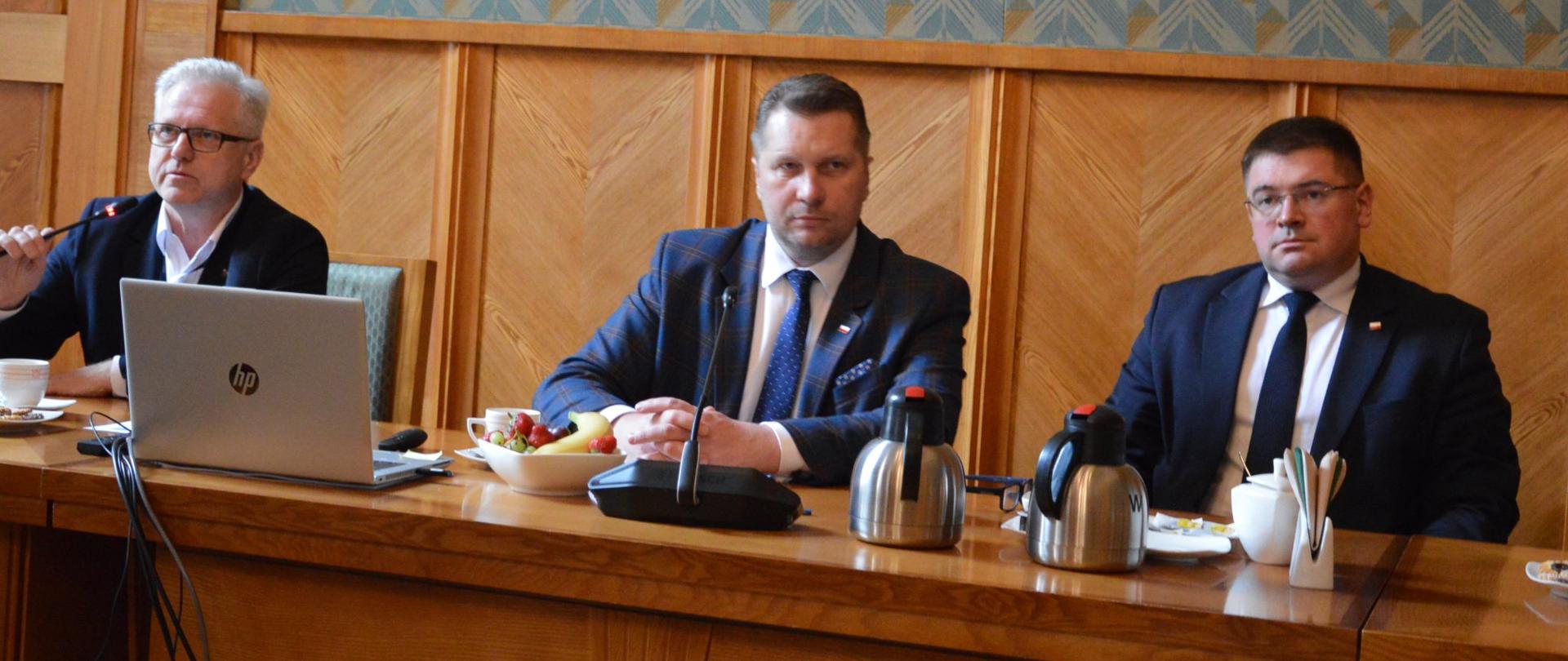 Minister Przemysław Czarnek oraz wiceminister Tomasz Rzymkowski siedzą przy stole obrad podczas spotkania