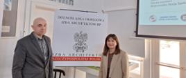 Osoby stojące pod ekranem w sali wykładowej