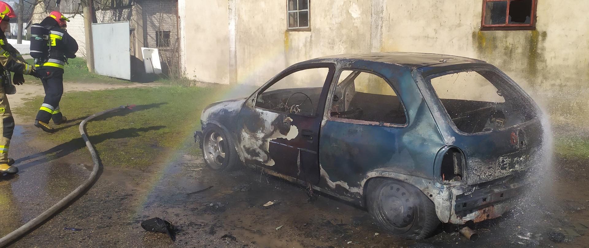 Samochód osobowy po pożarze. Karoseria samochodu opalona, szyby i reflektory pobite, elementy plastikowe spalone. Wnętrze samochodu wypalone. 