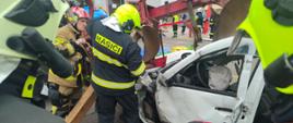Strażacy wykonują dostęp do osoby poszkodowanej zakleszczonej w pojeździe.