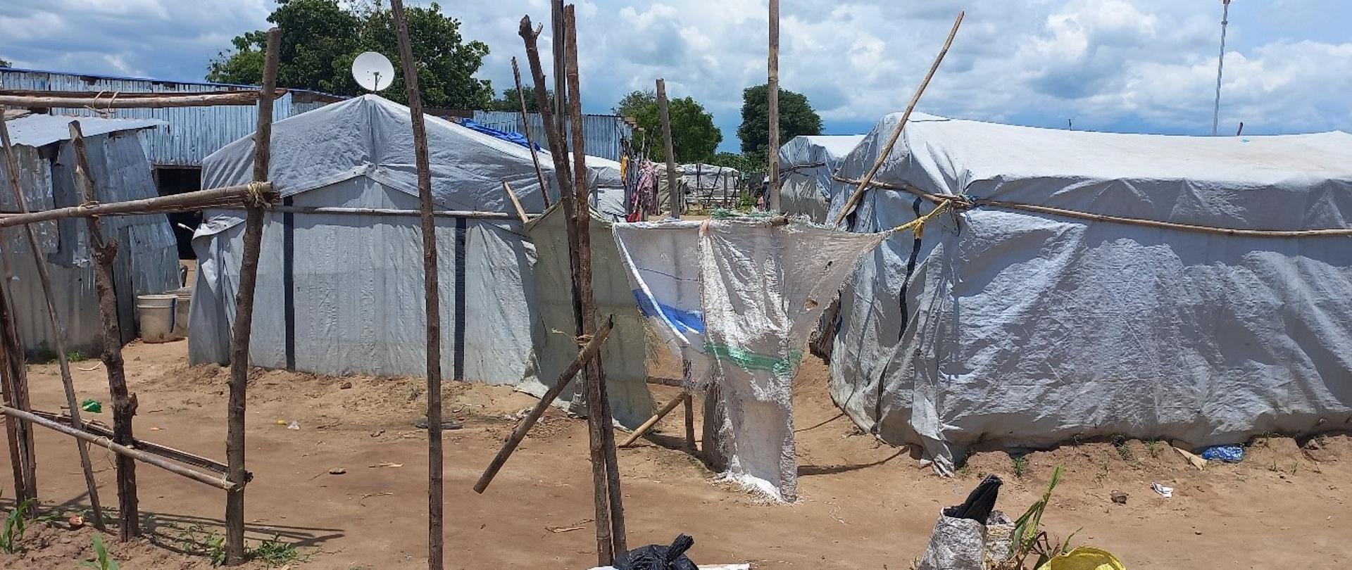 Białe namioty i prymitywne konstrukcje z gałęzi drzew