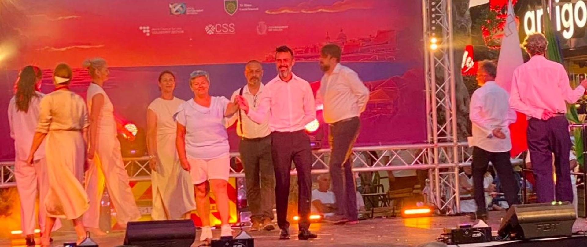 Na scenie widać pary tańczące poloneza. W tle plakat Connecting Through Culture.
