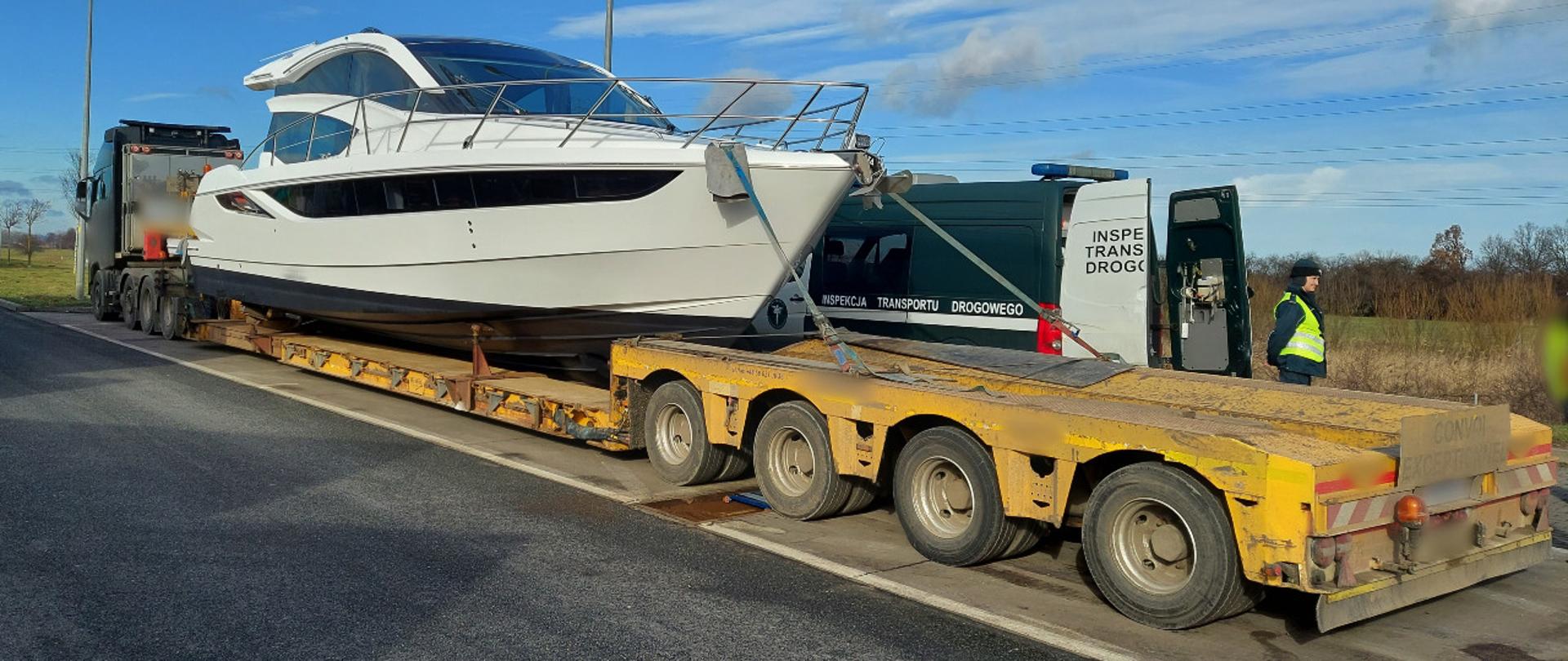 Gabaryt z jachtem zatrzymany do kontroli koło Gdańska przez inspektorów pomorskiej Inspekcji Transportu Drogowego. Nienormatywna ciężarówka stoi w punkcie kontrolnym ITD. Obok zestawu stoi oznakowany furgon oraz umundurowany funkcjonariusz pomorskiej ITD.