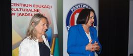 Dwie kobiety stoją przed banerem Centrum Edukacji Kulturalnej oraz Powiatowej Stacji Sanitarno Epidemiologicznej w Jarosław 