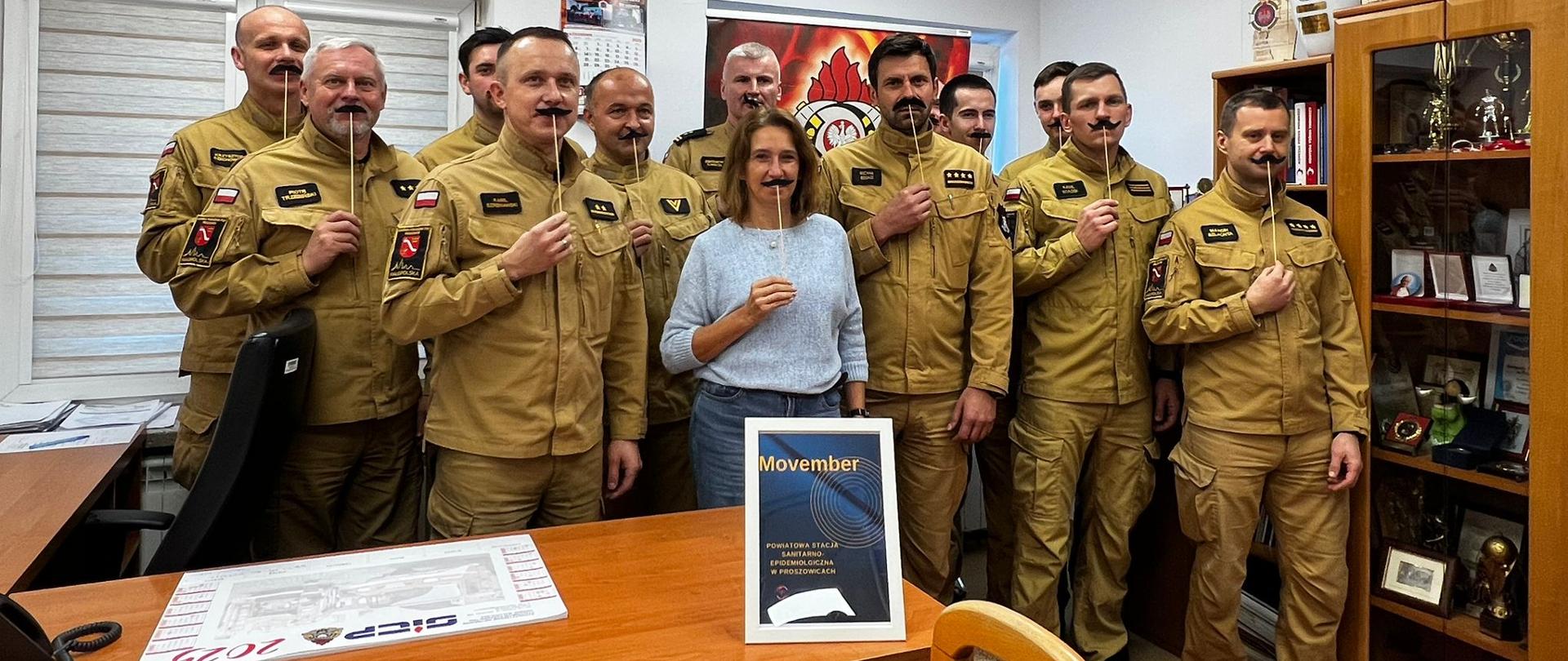 Kampania społeczna movember - strażacy stoją na zbiórce ze sztucznymi wąsami