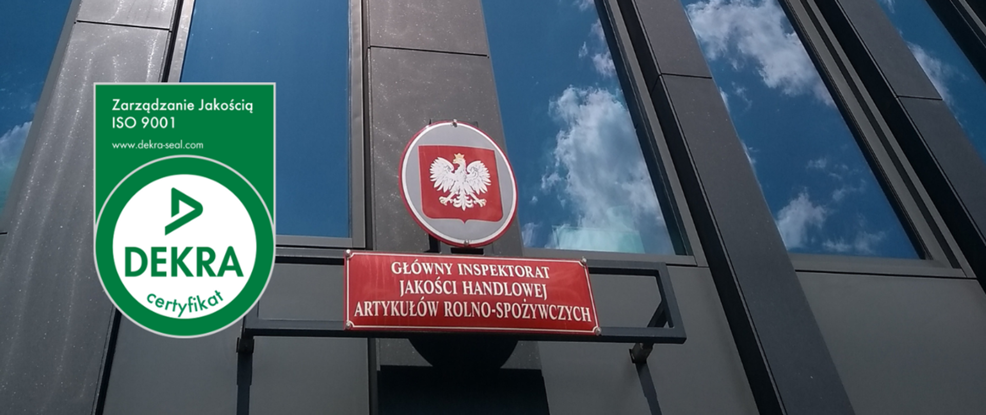 Po prawej stronie znajduje się godło Polski – biały orzeł na czerwonym tle – nad czerwoną tablicą z napisem:
„Główny Inspektorat Jakości Handlowej Artykułów Rolno-Spożywczych”.
Po lewej stronie widoczny jest zielony znak certyfikatu DEKRA, z napisem:
„Zarządzanie Jakością ISO 9001” oraz adresem strony internetowej www.dekra-seal.com"