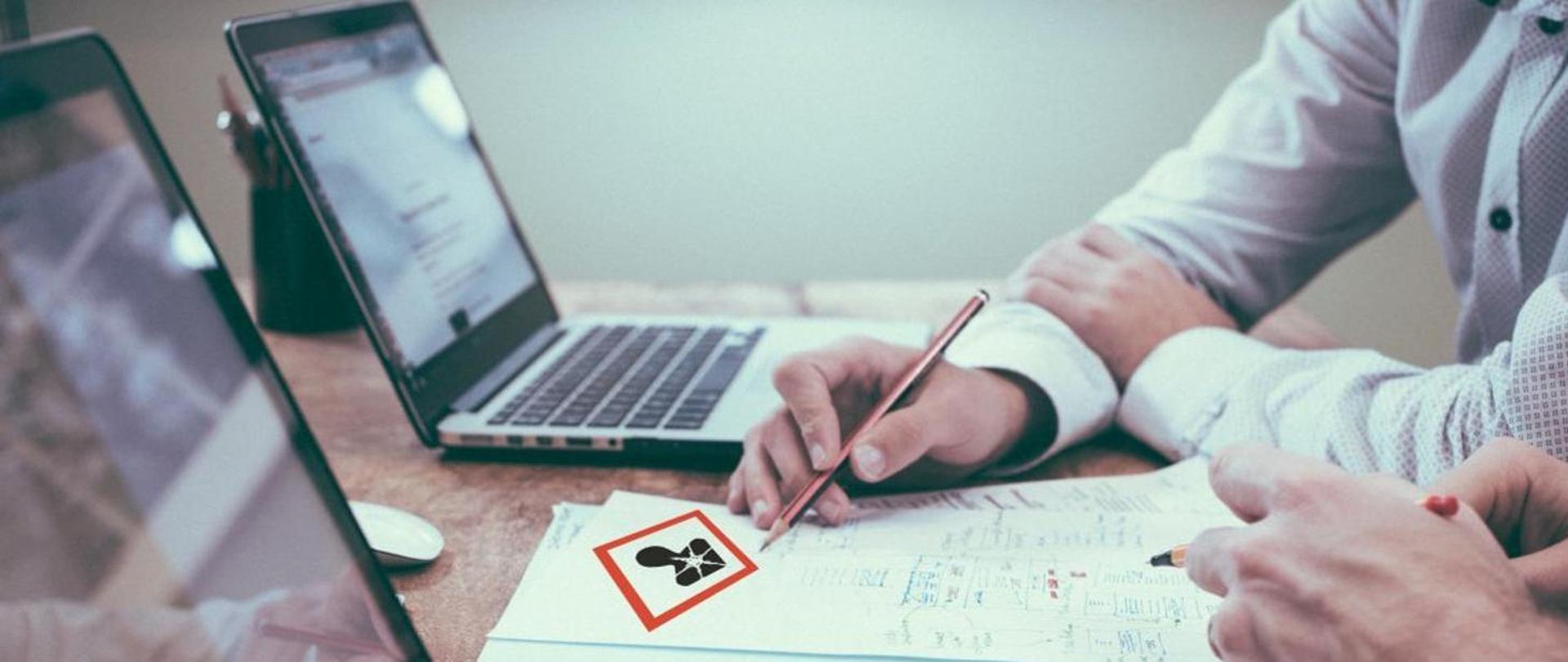 Grafika przedstawia osoby analizujące dokumenty przy biurku. 