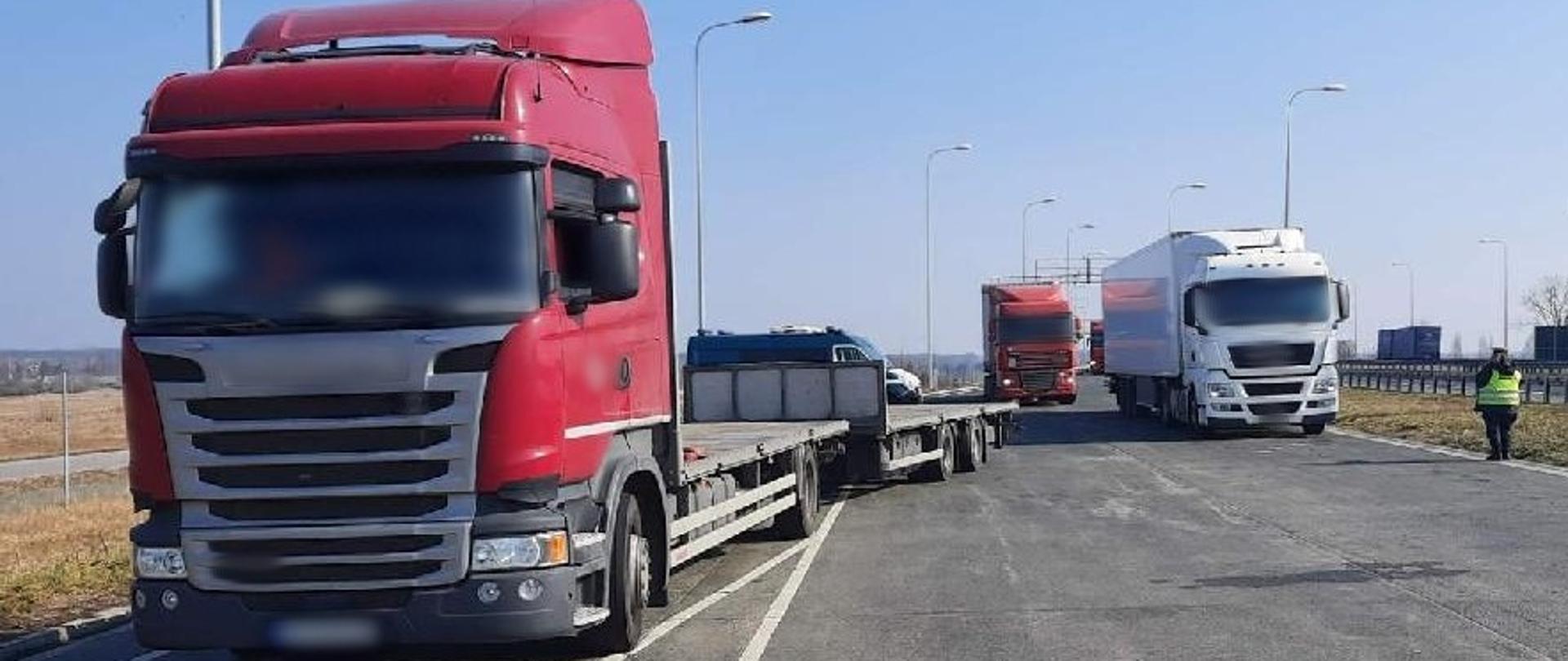 Zatrzymane ciężarówki stoją w punkcie kontrolnym przy drodze ekspresowej S8. W tle widoczny radiowóz ITD typu furgon. 