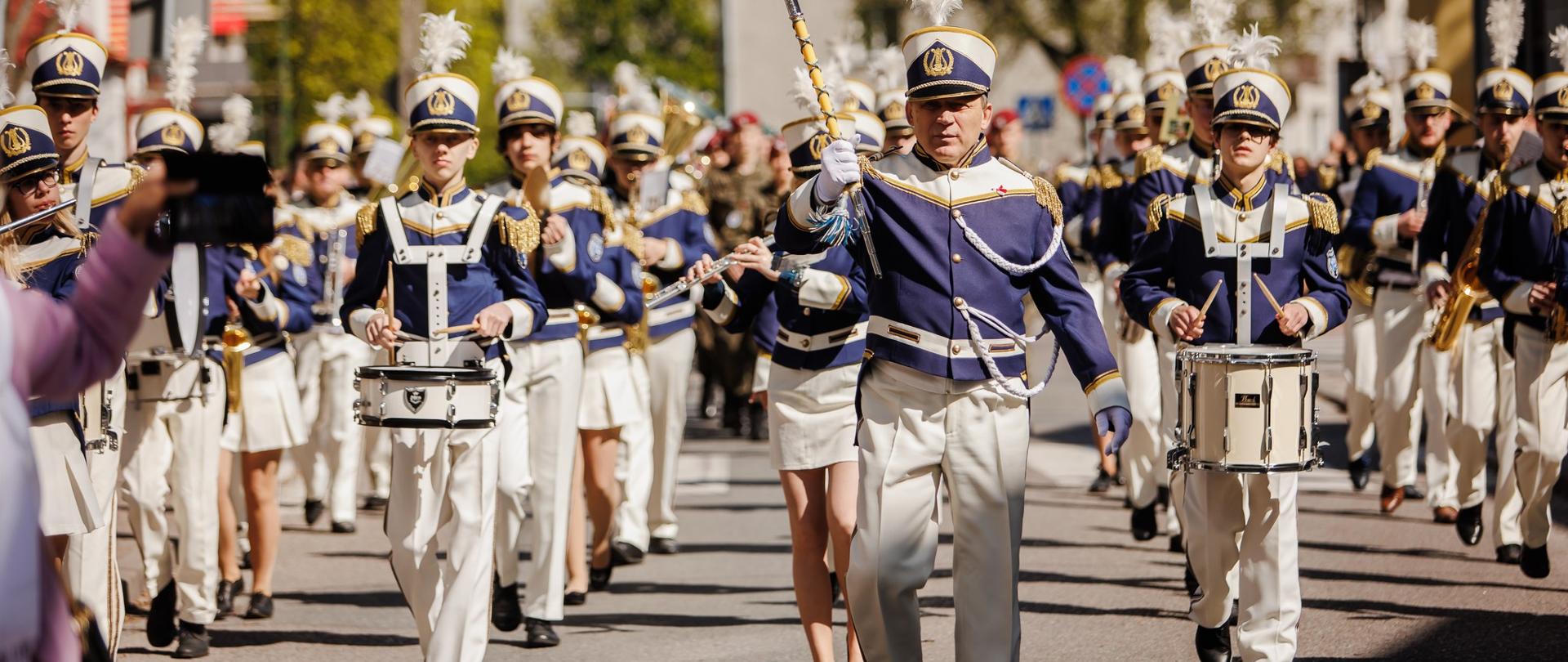 Fotografia przedstawia maszerującą orkiestrę 