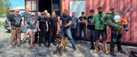 Pamiątkowe zdjęcie grupowe uczestników szkolenia z udziałem psów tresowanych w towarzystwie instruktorów i psa