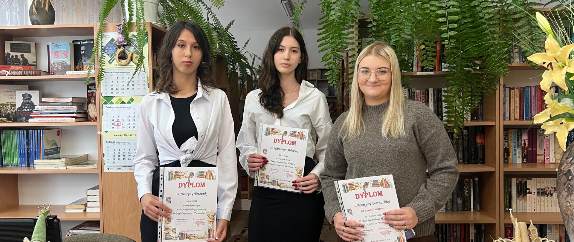 Uczestniczki konkursu pozują z dyplomami w bibliotece szkolnej