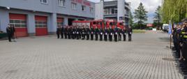 
Zdjęcie przedstawia strażaków, którzy stoją na placu przed komendą podczas uroczystości obchodów dnia strażaka
