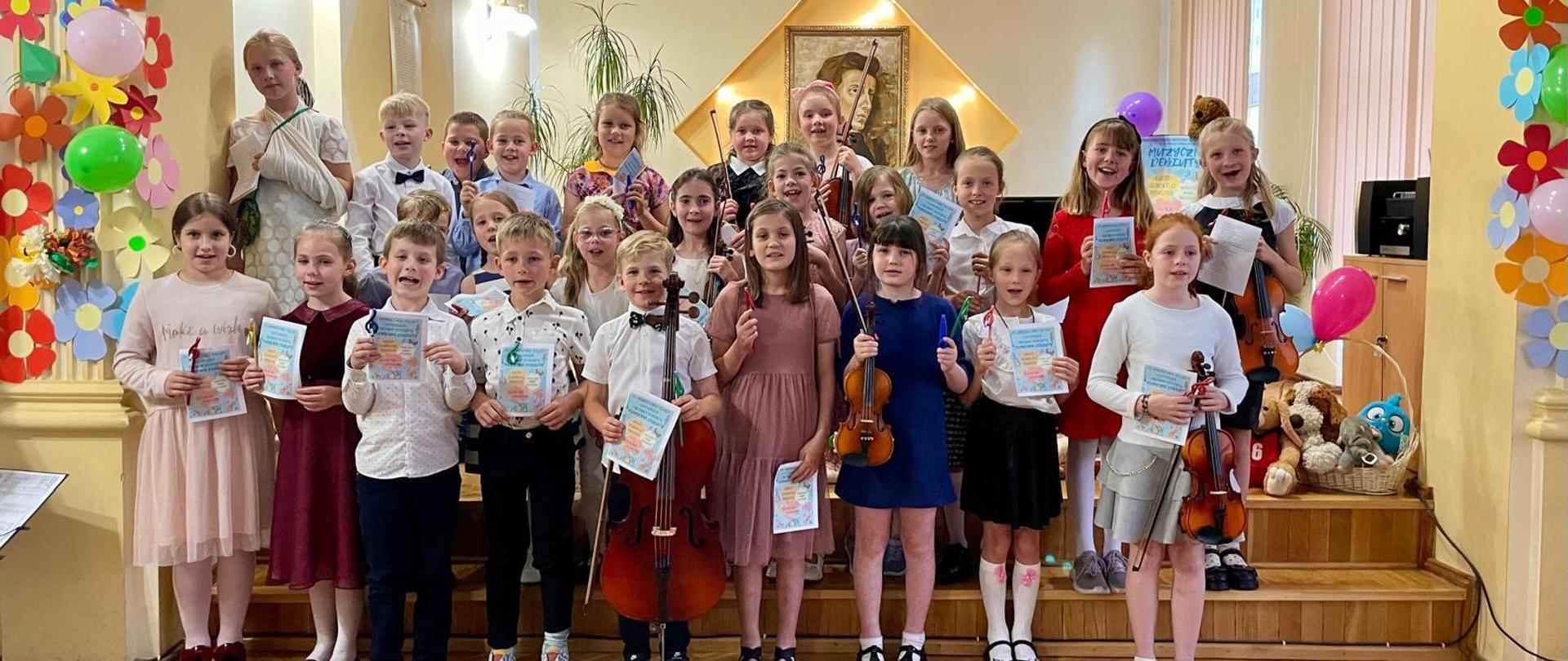 Galeria 45 zdjęć z koncertu klas pierwszych pt. "Muzyczne Debiuty", który odbył sie 28 maja 2024 r. w auli PSM w Kłodzku. Młodzi wykonawcy grają na różnych instrumentach na scenie auli.