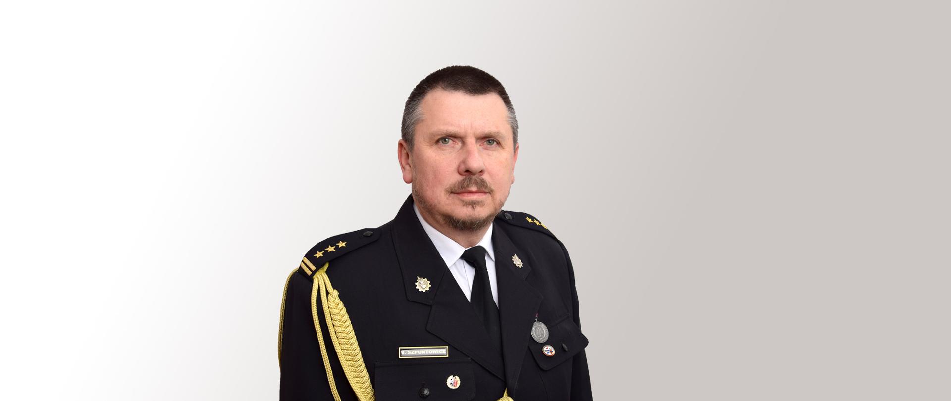 Zdjęcie portretowe komendanta st. bryg. Jacek Szpuntowicz na jasnym tle w mundurze galowym
