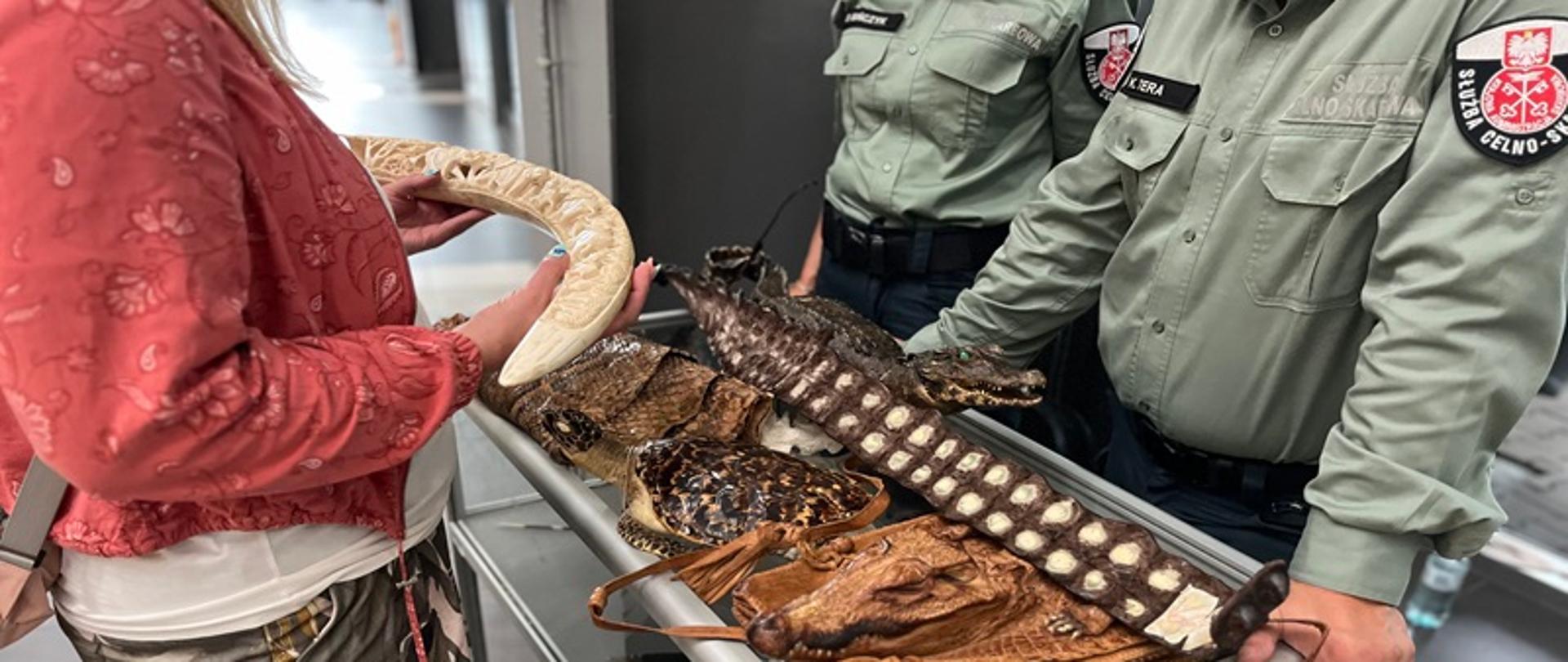  Stoisko KAS w Porcie lotniczym-kobieta ogląda pamiątki z wakacji. Przed nią stoją funkcjonariusze. 