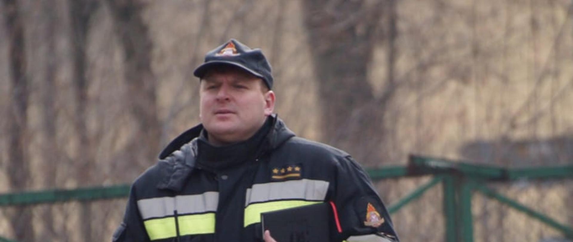 Strażak stojąc w umundurowaniu.