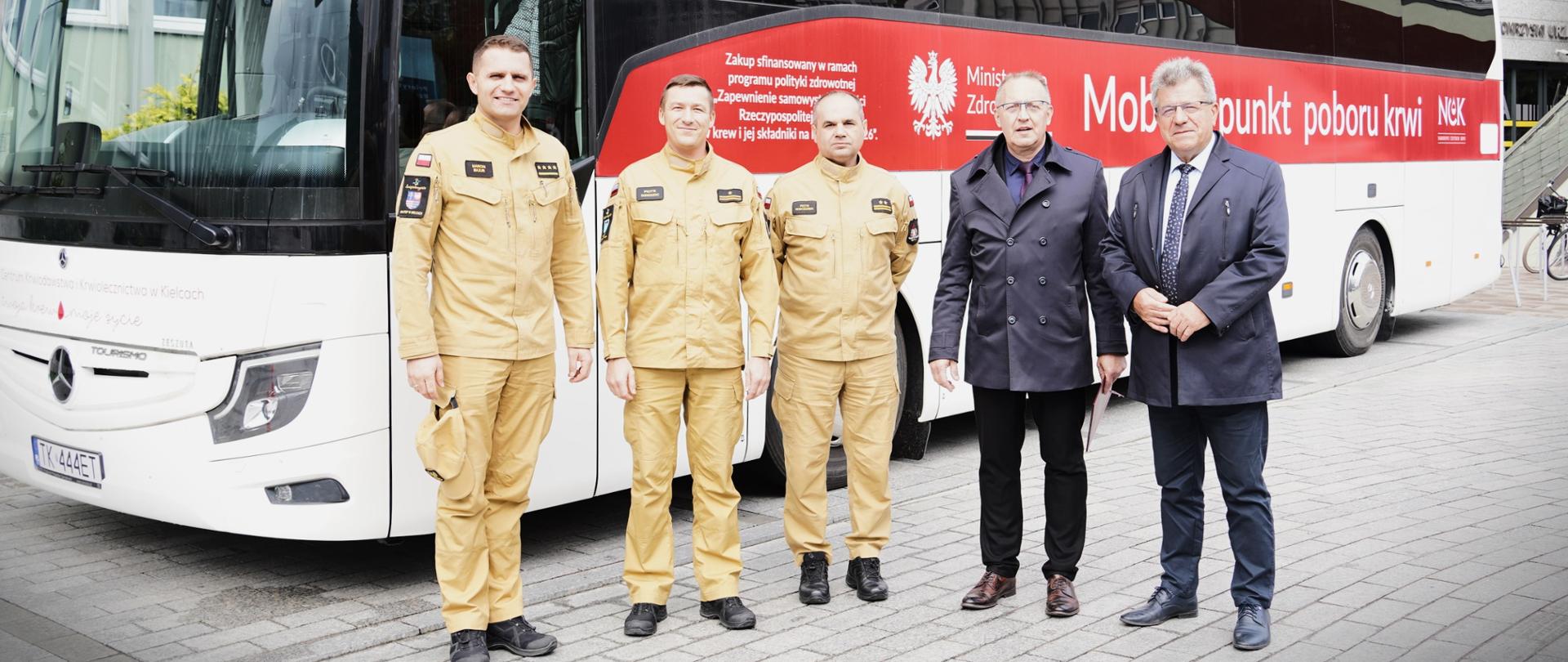 Przed autobusem do poboru krwi stoją strażacy i wojewoda