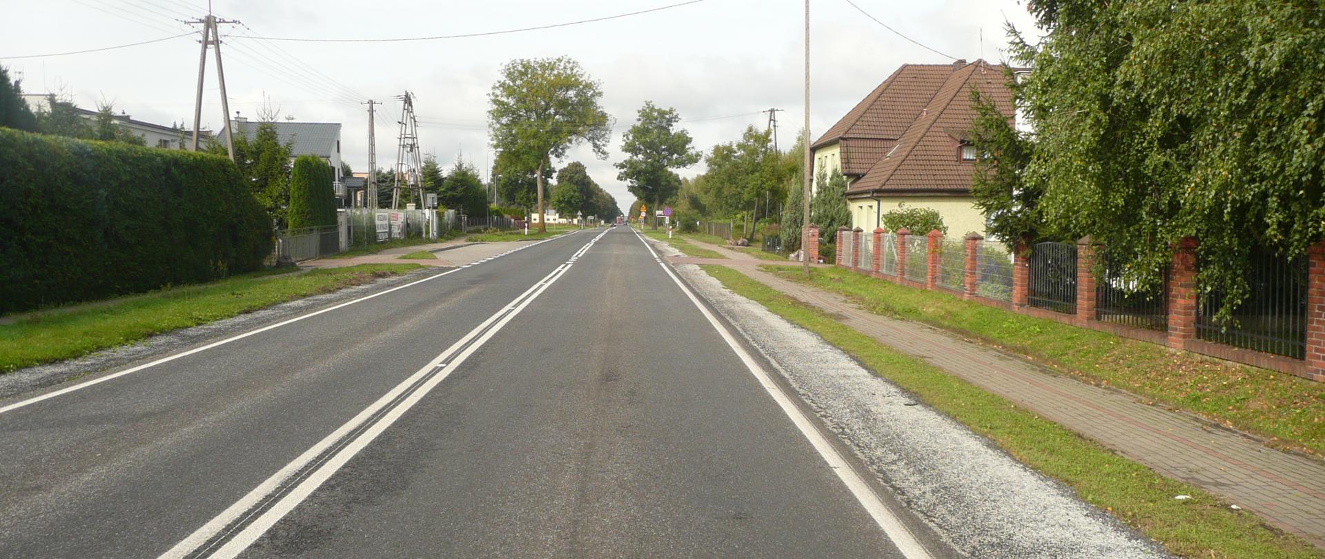 Na zdjęciu widoczna droga krajowa nr 10 przebiegająca przez teren zbudowany. Po jednym pasie w każdą stronę. Zarówno po lewej jak i prawej stronie widoczne zabudowania