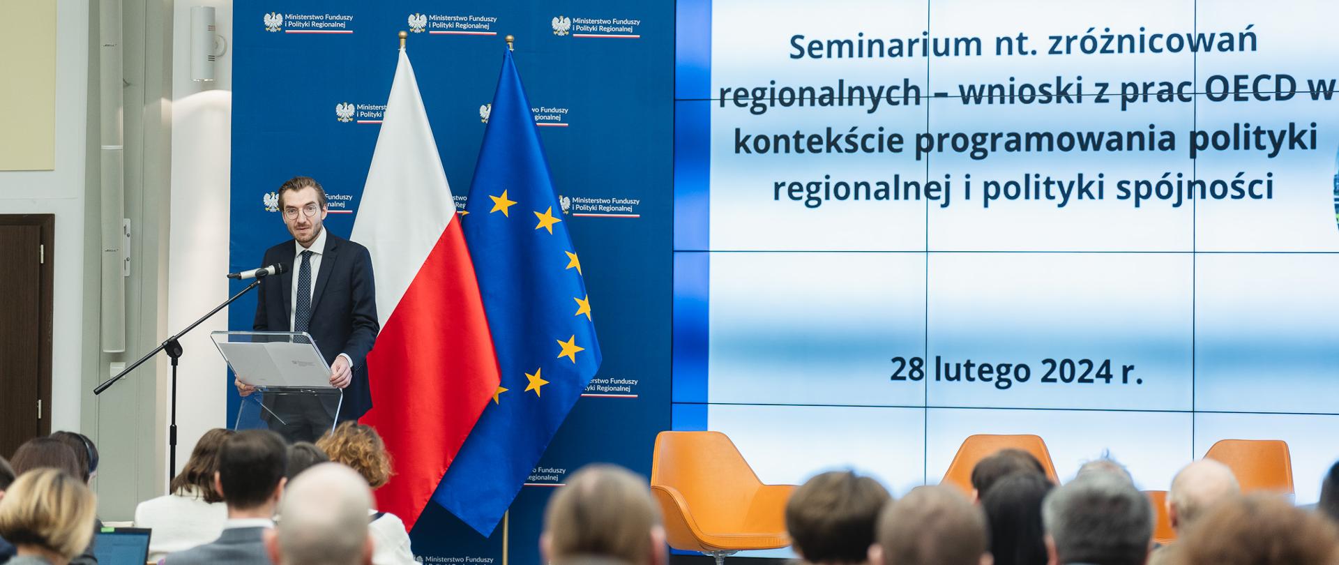 Wiceminister Jan Szyszko stoi z lewej strony przy szklanym pulpicie.