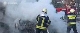 Dwóch ukraińskich strażaków gasi pożar, ubrani są w mundury otrzymane z Polski z napisem STRAŻ
