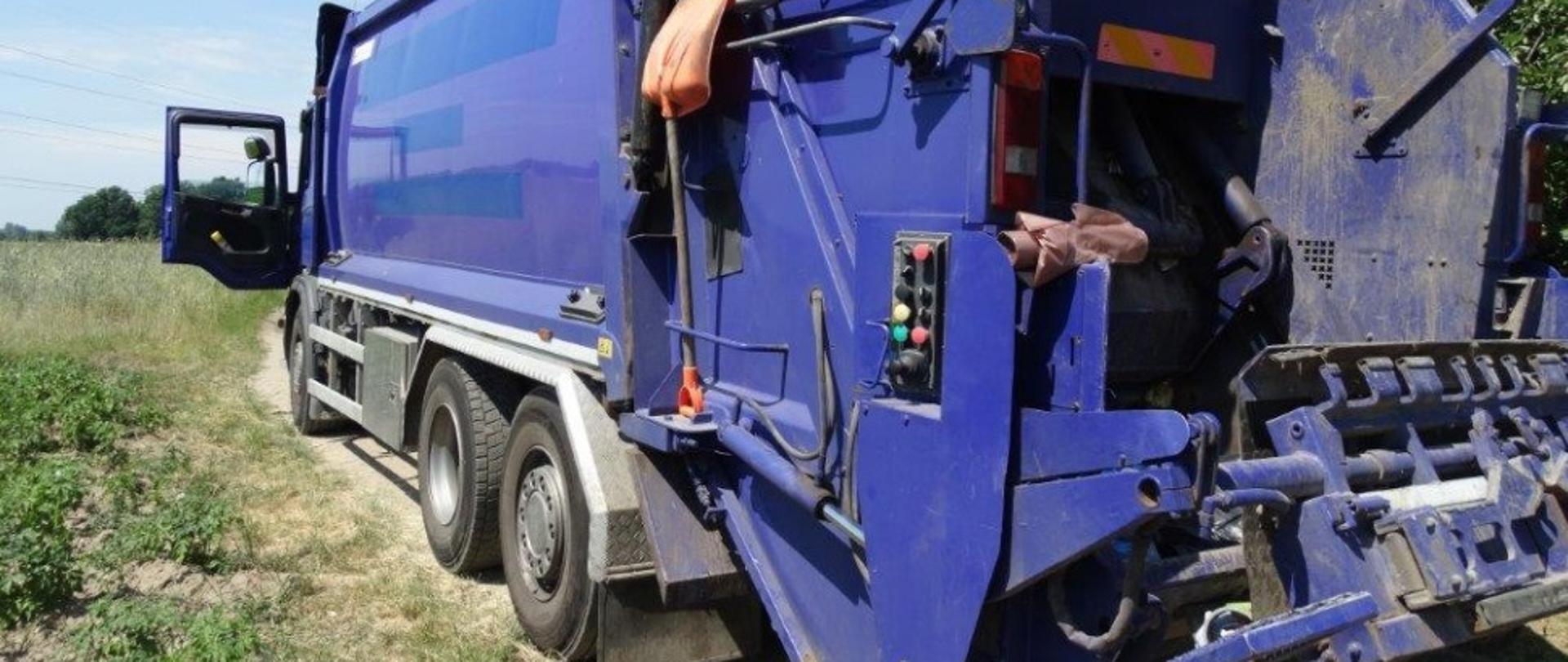 Na zdjęciu śmieciarka koloru niebieskiego na drodze polnej