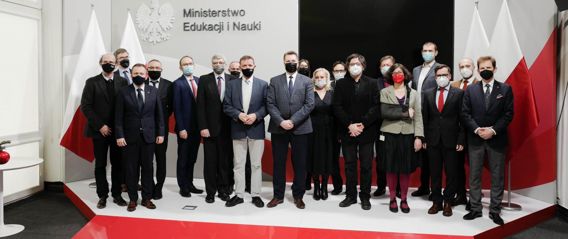 Wręczenie powołań do składu Rady Naukowej Instytutu Badań Edukacyjnych, nowi członkowie rady IBE stoją w towarzystwie ministra Przemysława Czarnka.