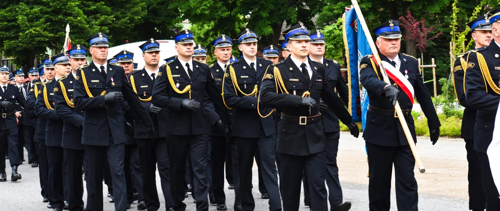 Zdjęcie przedstawia maszerujących strażaków
