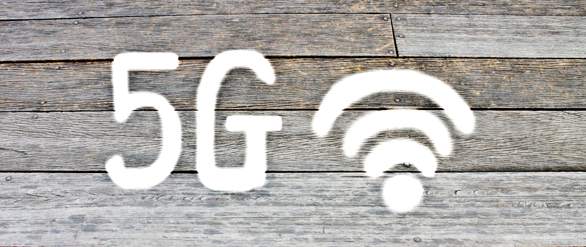 Napis 5G oraz ikona zasięgu na tle desek