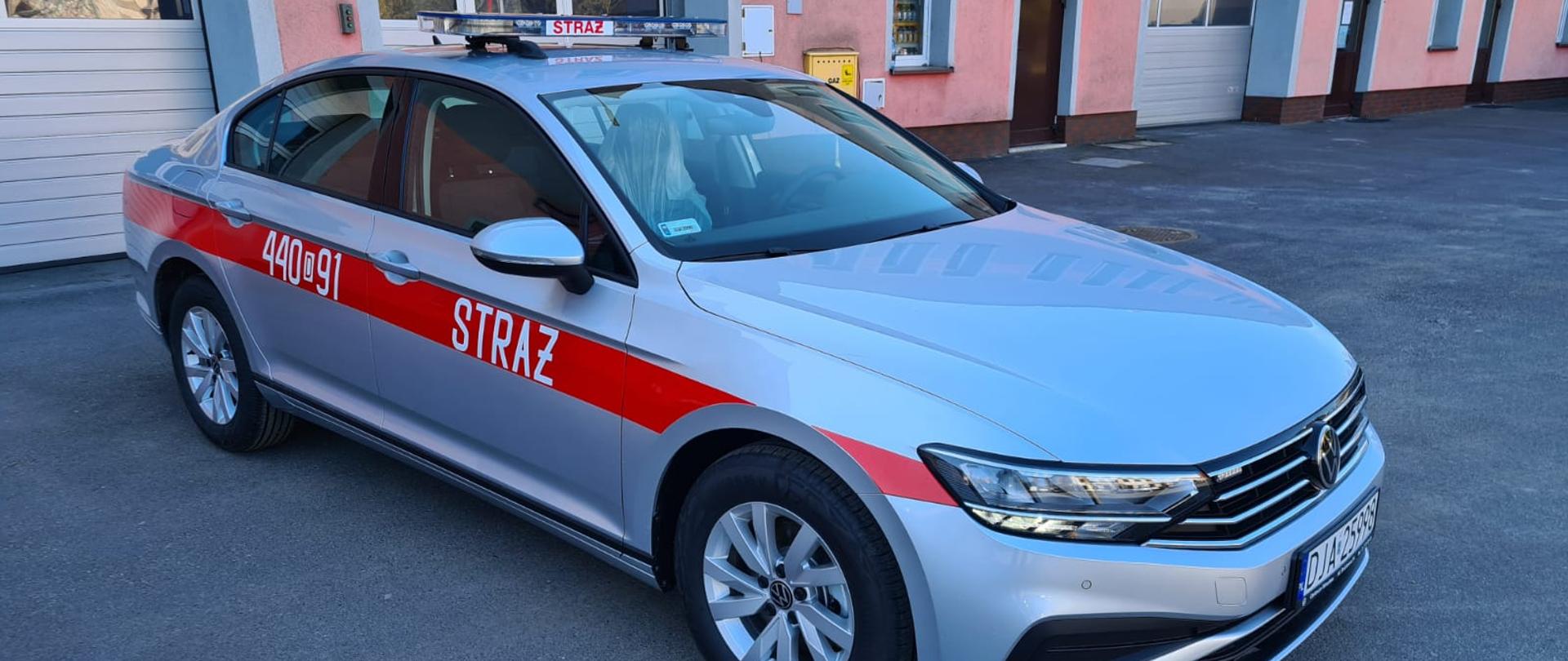 Obraz przedstawia nowy lekki samochód operacyjny. W tel budynek komendy.