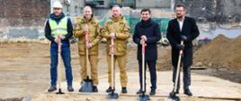 Wojewoda Śląski, Śląski Komendant Wojewódzki Prezydent Miasta Katowice oraz Komendant Miejski PSP w Katowicach, przedstawiciel firmy budowlanej na tle budowanej nowej Jednostki Ratowniczo-Gaśniczej nr 3 z symboliczną wkopaną pierwszą łopatą.
