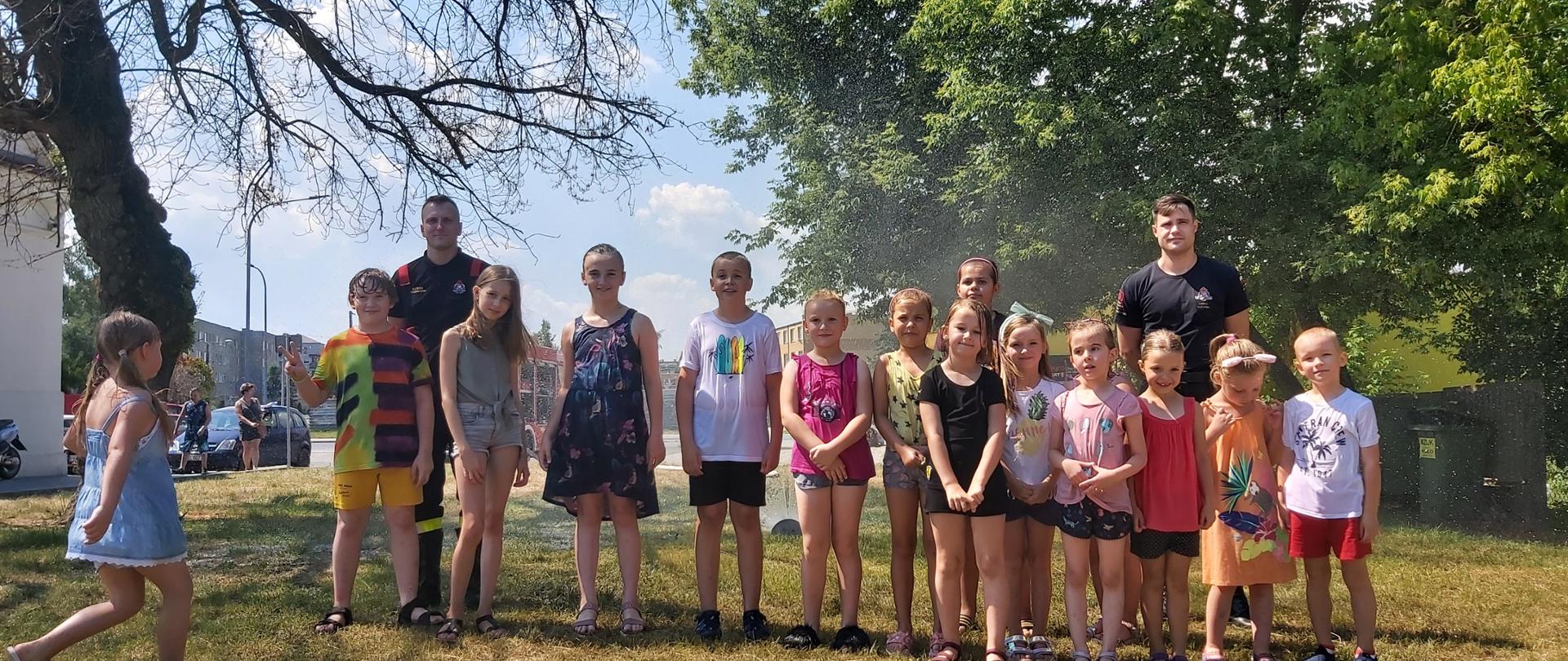 Zdjęcie przedstawia strażaków z grupą dzieci, które brały udział w zajęciach zorganizowanych przez straż.