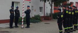 Zdjęcie przedstawia strażaków podczas uroczystego wciągnięcia flagi na masz w celu uczczenia kolejnej rocznicy odzyskania przez Polskę Niepodległości. 