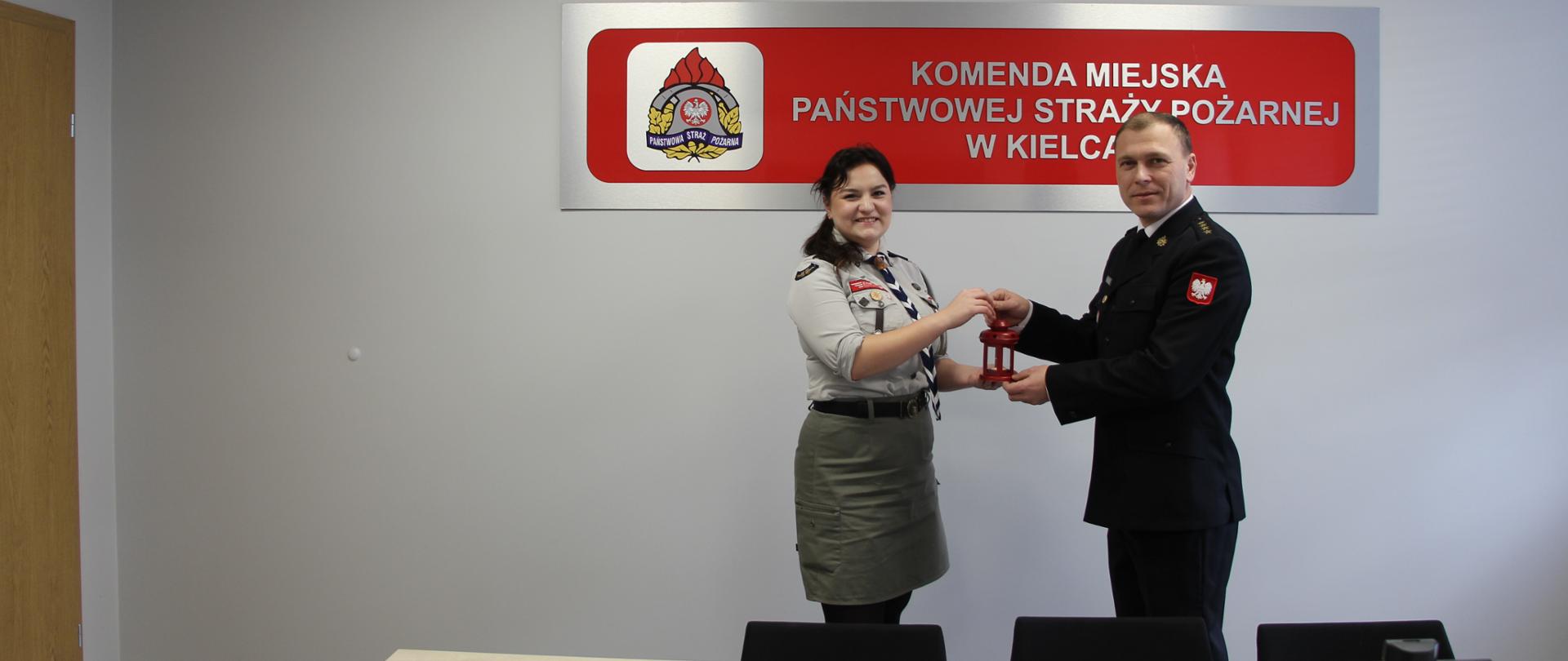 Zdjęcie przedstawia naczelnika Wydziału Organizacyjno-Kadrowego odbierającego symboliczne Betlejemskie Światełko Pokoju od przedstawiciela Związku Harcerstwa Polskiego.