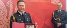 Na zdjęciu widoczny bryg. Maciej Wolański trzymający ryngraf otrzymany z okazji przejścia na zaopatrzenie emerytalne, po prawej stojący bryg. Przemysław Przęczek Zastępca Małopolskiego Komendanta Wojewódzkiego PSP 