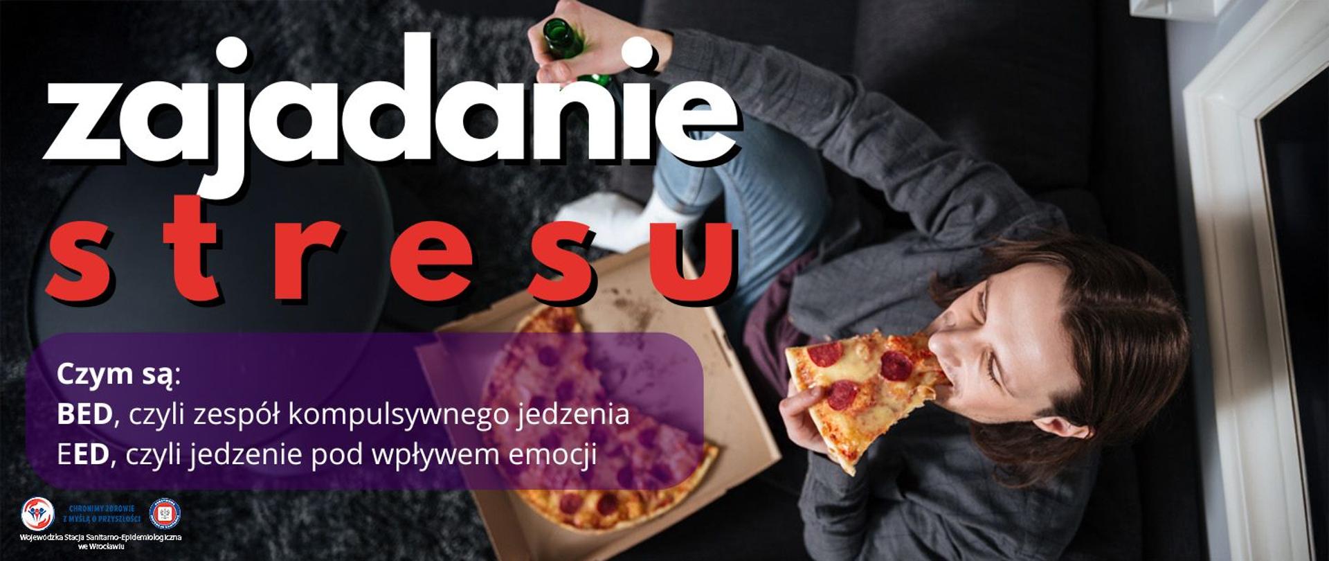 Mężczyzna siedzący w pokoju zjadający kawałek pizzy, przed nim na stoliku leży pudełko z pizzą.