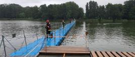 Strażacy rozwijający linię gaśniczą przez most pływający prowadzący na Wyspę Edwarda w Zaniemyślu
