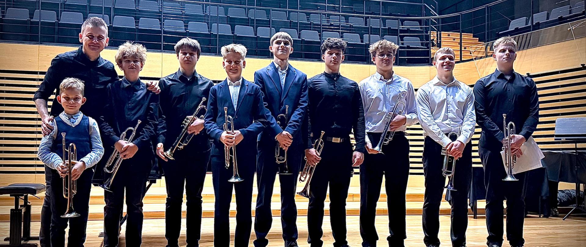 Nauczyciel ze wszystkimi uczniami stoi na scenie.