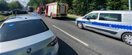 Na pierwszym planie (od lewej): nieoznakowany radiowóz osobowy mazowieckiej Inspekcji Transportu Drogowego z włączonymi światłami niebieskimi uprzywilejowania w ruchu drogowym. Obok pojazdu stoi inspektor, który odczytuje dane cyfrowe z tachografów i kart kierowców ciężarówek biorących udział w wypadku, W tle: rozbite pojazdy osobowe i ciężarowe blokują trasę. Obok miejsca wypadku stoi wóz gaśniczy Straży Pożarnej, radiowóz oznakowany Policji i furgon Służby Drogowej. 