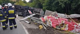 Samochód z przyczepą leży poza drogą. Widać wełnę mineralną.