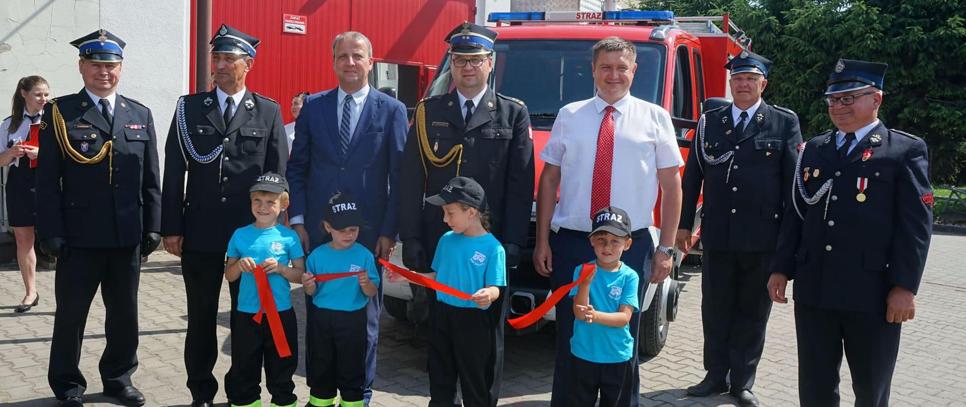zdjęcie grupowe przed remizą i samochodem strażackim strażaków PSP i OSP , dzieci z MDP i wojewody wielkopolskiego