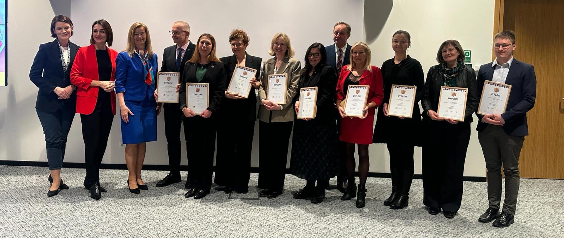 Kilkanaście osób stojących w szeregu trzyma dyplomy dla najlepszych szkól w regionie według rankingu Perspektywy 2024