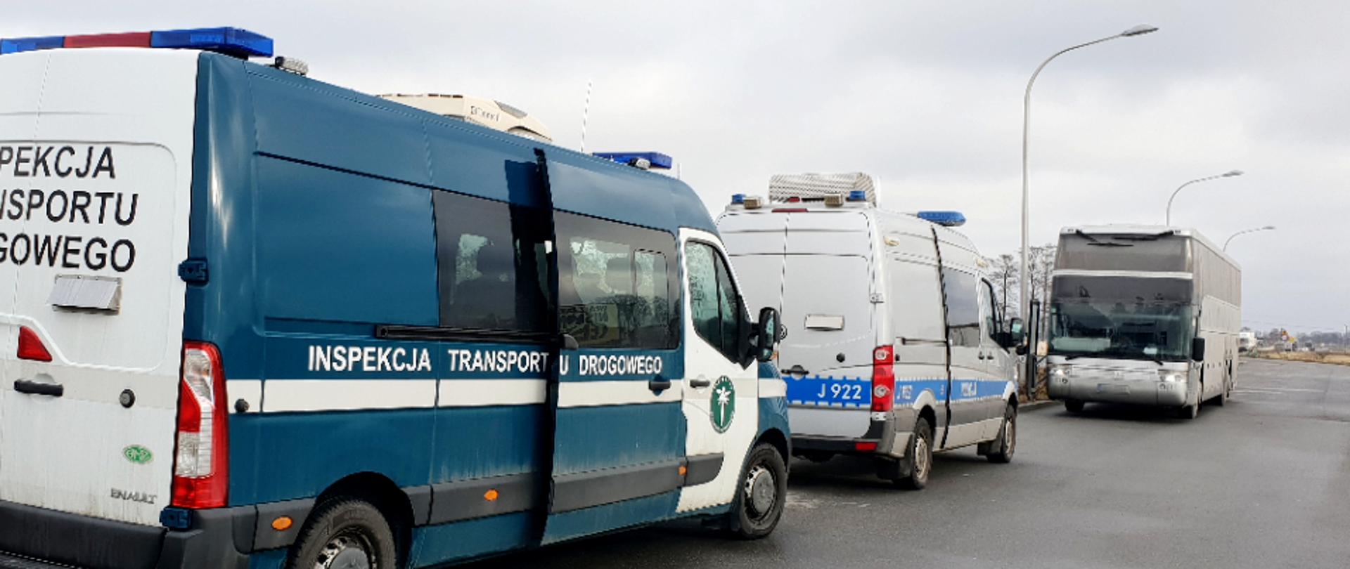 Autobus zatrzymany przez inspektorów opolskiej Inspekcji Transportu Drogowego. Na pierwszym planie radiowozy Inspekcji Transportu Drogowego i Policji. W oddali zatrzymany autobus, którym realizowany był przewóz osób z Ukrainy do Czech.