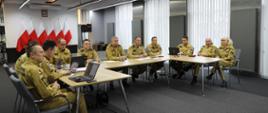11 funkcjonariuszy PSP siedzi przy stole podczas odprawy