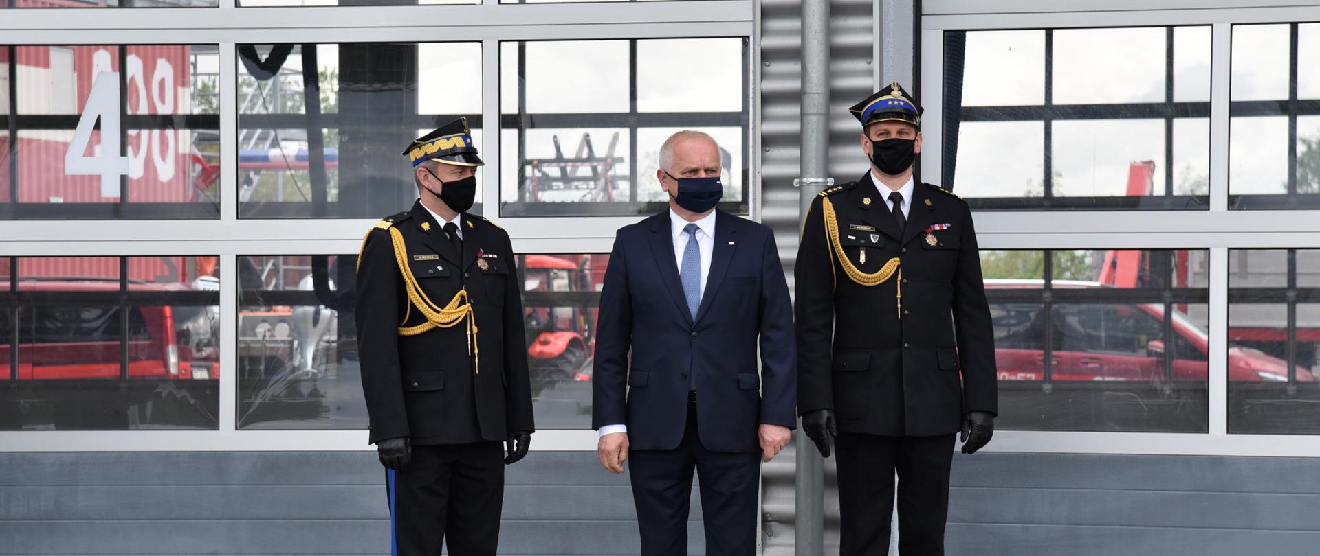 Wojewoda, zastępca komendanta głównego i komendant wojewódzki stoją przed budyniem komendy czekając na odznaczonych 