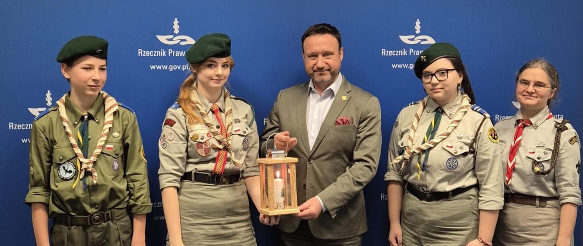 Harcerze z Betlejemskim Światełkiem Pokoju. Na zdjęciu jest czterech harcerzy po środku Dyrektor Generalny, który otrzymuje światełko.