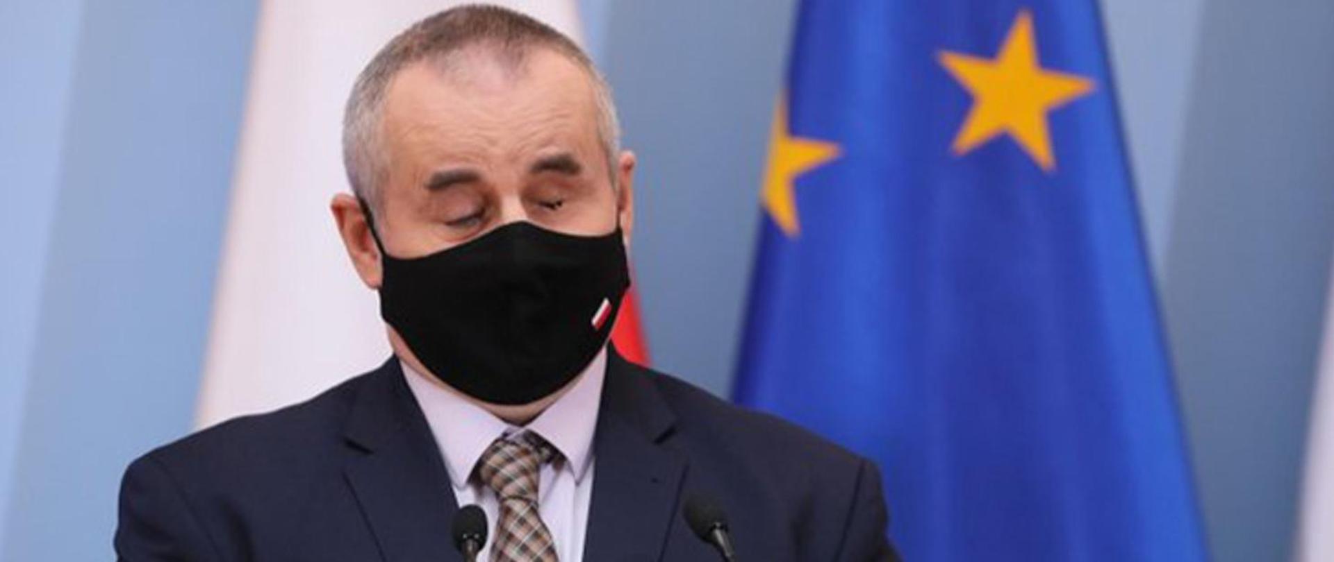 Na zdjęciu znajduje się niewidomy mężczyzna, który mówi do mikrofonów.