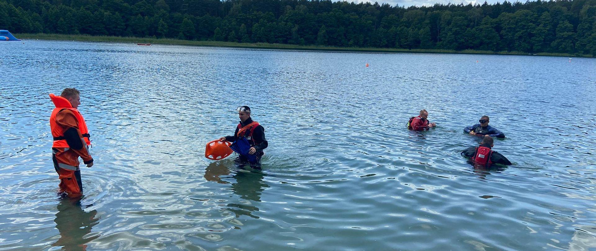 Strażacy w wodzie podczas ćwiczeń ze sprzętem.