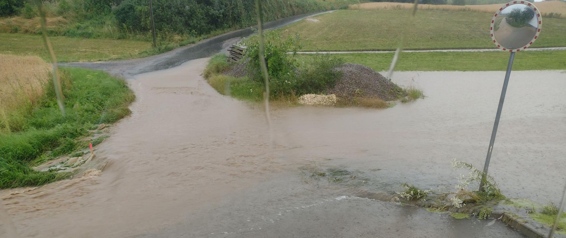 Na zdjęciu widzimy zalane skrzyżowanie dróg. Zdjęcie wykonane z kabiny samochodu pożarniczego.